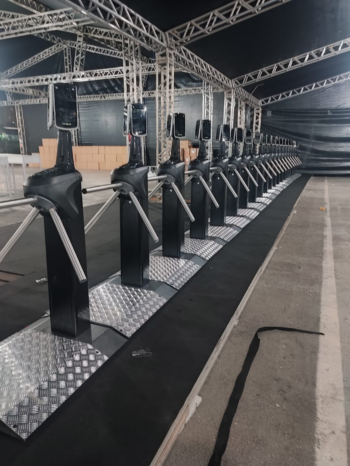 Fileira de catracas inteligentes do Grupo INAC equipadas com reconhecimento facial para controle de acesso de alta performance em grandes eventos e festivais.